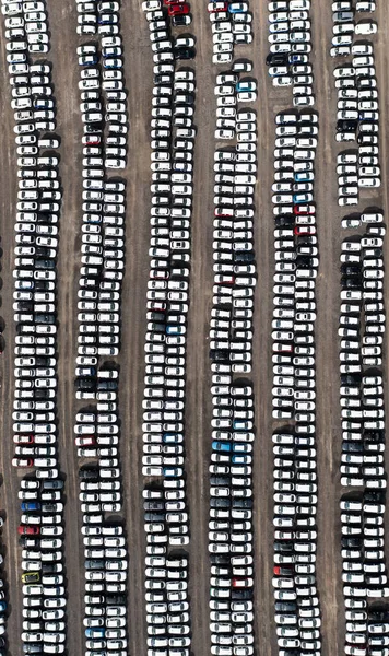 An aerial view of rows of newly built cars and vehicles ready for export and import and delivery to sales dealerships