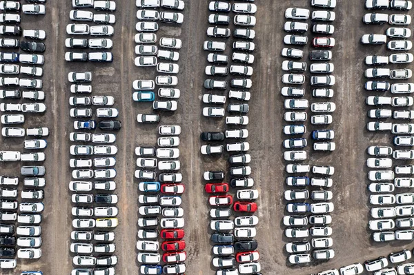 An aerial view of rows of newly built cars and vehicles ready for export and import and delivery to sales dealerships