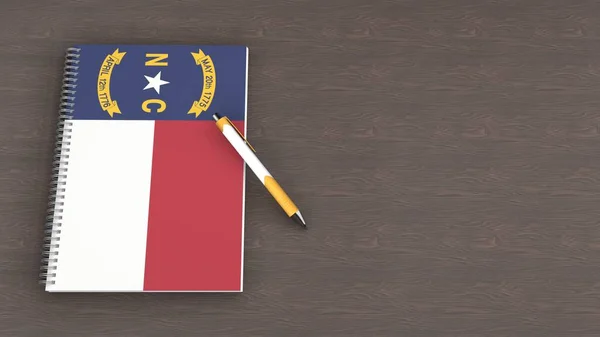 Kuzey Carolina bayrağı ve yalancı bir kalemin olduğu bir defter.