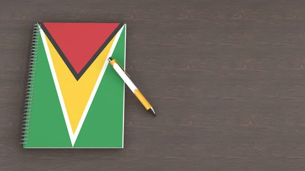 Üzerinde Guyana bayrağı ve yalancı bir kalem olan bir defter.