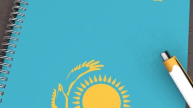 Üzerinde Kazakistan bayrağı ve yalancı bir kalem olan bir defter.