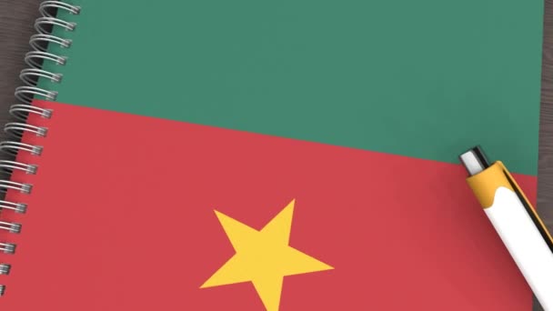 Ein Notizbuch Mit Der Flagge Kameruns Und Einem Lügenstift — Stockvideo