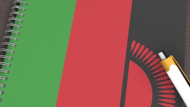 Ένα Σημειωματάριο Σημαία Του Μαλάουι Και Ένα Στυλό Που Βρίσκεται — Αρχείο Βίντεο