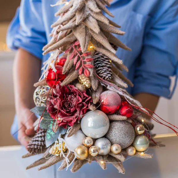 クリスマスの構図手作りのバラップ女性の手に赤いボールとクリスマスツリー — ストック写真