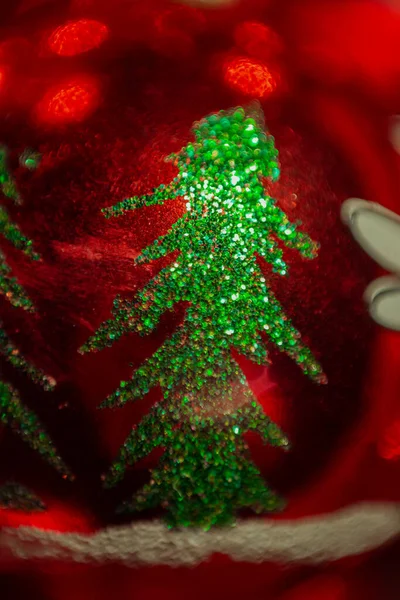 Makro fotoğrafçılık. Soyut görüntü. Kırmızı topun üzerindeki pullardan yapılmış yeşil Noel ağacı.