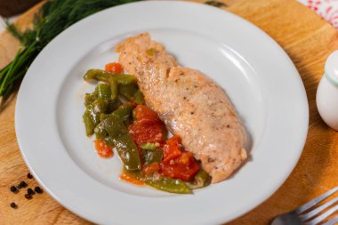 Beyaz tabakta çalı fasulyeli morina filetosu.