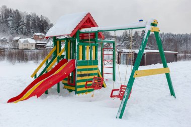 Çocuk parkı, kay ve sallan. Karlı bir kış gününde.