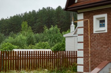 Evin arkasında karışık yeşil bir orman görülebilir. Bir yaz günü fotoğraf..