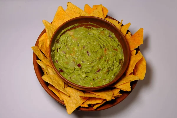 Mexican guacamole sauce and tortilla chips on a isolated white background. Guacamole bowl with nachos chips. Top view.