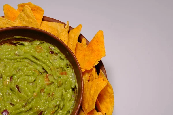 Mexican guacamole sauce and tortilla chips on a isolated white background. Guacamole bowl with nachos chips. Place for text, close up view of a part the plate.