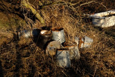 Köyde paslanmış eski kovalar var. Kuru ot ve bitki örtüsü olan alanın doğal arkaplanı.