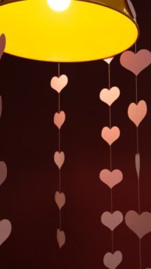 Kırmızı arka planda uçan kırmızı kağıt kalpler. Sevgililer Günü. Aşkın sembolü. Güzel uçan pembe kalpler. Sevgililer Günün kutlu olsun. Lambanın altında kalpler. Sevgiyle dolu. Aşk günü.