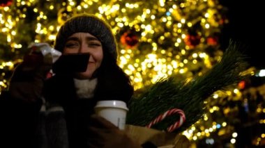 Mutlu kadın çikolatayı seviyor. Arka planda noel ağacı Kamerada poz veren manken kız.