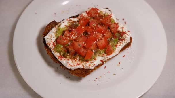 Avocado sandwiches, de helft van avocado, met pinda 's en pompoenpitten, tomaten op een witte achtergrond draaien rond — Stockvideo