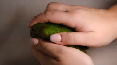 Kadın elleri avokadoyu ikiye böler. Taze olgun avokado, sağlıklı kahvaltı, vejetaryen yemeği.