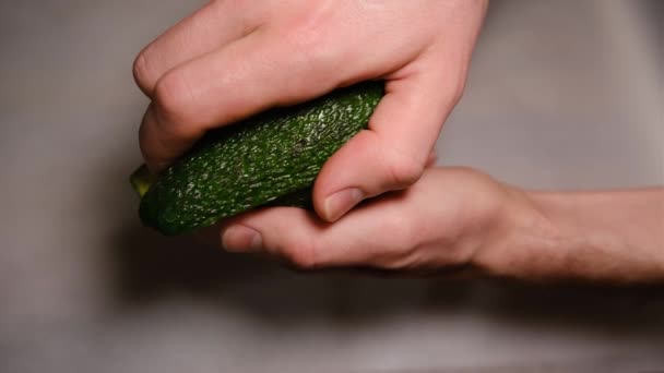 Manos masculinas abren aguacate por la mitad. Aguacate fresco maduro, Desayuno saludable, Comida vegetariana — Vídeos de Stock