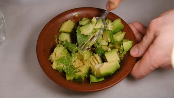 Mashed avocado in a bowl closeup view. Healthy vegan vegetarian food sauce or face mask for you — ストック動画