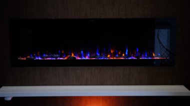 Elektrikli şömine üzerinde yapay parlayan alev, iç dekorasyon, turuncu arka ışıklandırmalı kristaller üzerinde turuncu ve mavi alev.