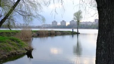 Sumy, Ukrayna 'daki şehir gölünde gün batımında balıkçı. Gökyüzünden güzel yansıyor ve sudaki bulutlar