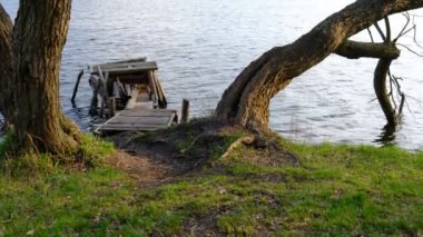 Autumn scene - lake and destroyed wooden pier. Old rotten wooden pier with missing planks with bench on a lake in the forest at autumn.