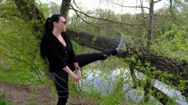 Beautiful sport woman doing stretching fitness exercise in city park at tree log. Yoga postures