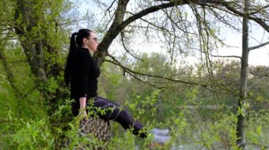 Yavaş çekim genç zinde kadın güneşli ormanın arka planında ağaç kütüğünde mekik çekiyor. Açık hava sporu, sağlıklı yaşam tarzı. Ağaçlar arasında tahta terasta karın kaslarını çalıştıran sportif bir kadın..