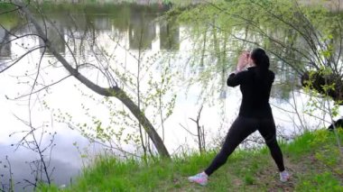 Bahar parkında çalışan güzel bir kadın. Yaz konsepti çömelme, fitnes açık hava. Yavaş çekim