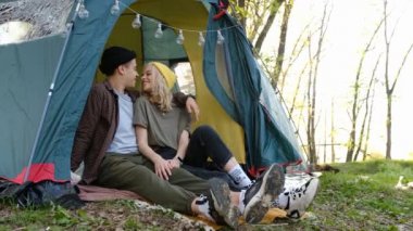 Romantic couple camping outdoors and sitting in a tent. Happy Man and woman on a romantic camping vacation. Letters on soks mean RUSSIAN WARSHIP GO FUCK
