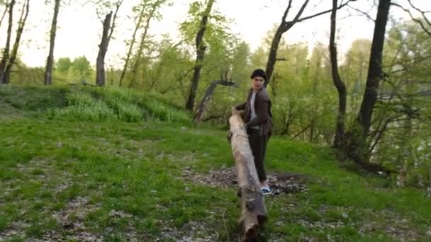 Young man carry large log through the forest for sitting near the fireplace, side view. — Stock Video