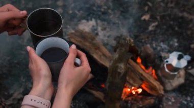 Ateş Çukurlu Kamp Bölgesi 'ne aşık bir çift ve sıcak çay ve kahveli iki teneke bardak. Yanan Kamp Ateşi.