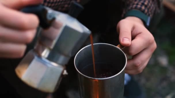 森の中の若いペア 女性はアルミニウム製のコーヒーメーカーからお茶を注ぐ カップにコーヒーを注ぐキャンプカップル — ストック動画