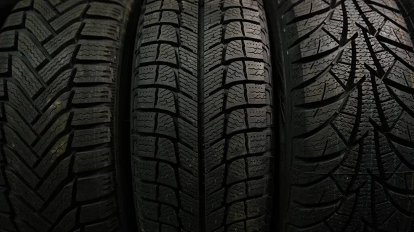 three Different Winter tires for cars with slow moving from down to the top on a shop stand.