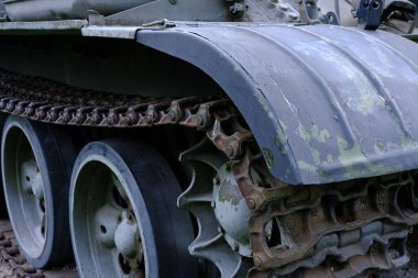 Depoda duran yeşil tırtılın ön tarafı. Tekerlekleri yakın çekimde yerde duruyor..