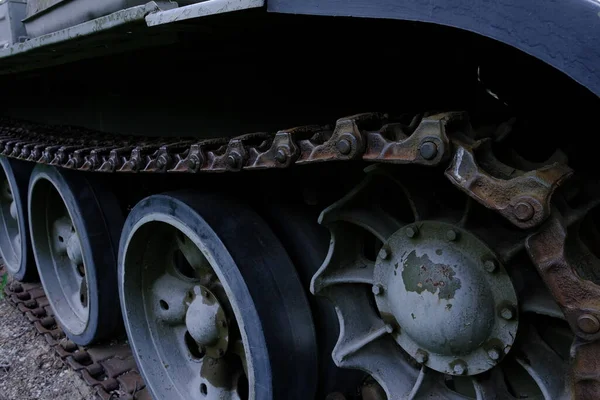 view of the front part of the green caterpillar of the tank standing on the ground with the wheels close-up.
