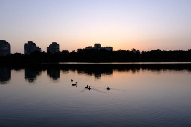 Sumy City şehir merkezinde, gün batımında gökdelenler ve nehir üzerinde renkli gökyüzü olan bir panorama..