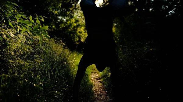 man walks on hands in the forest at sunset, sunrise,