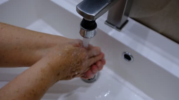 古い女性自宅のバスルームで石鹸とお湯で手を洗う女性は コロナウイルスの発生防止のための手の衛生を浄化シンクします 手を頻繁に洗うことによるコロナウイルスパンデミック対策 — ストック動画