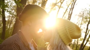 Yavaş çekim 2x Gün batımına karşı öpüşmeyi bekleyen genç ve güzel bir çiftin portresi.