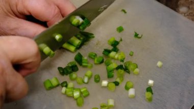 Yaşlı kadın elleri mutfakta taze soğan kesiyor..