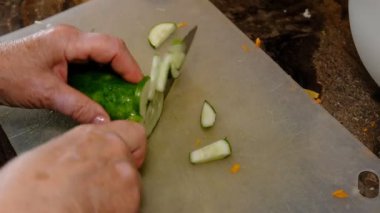 Sağlıklı beslenme, diyet konsepti. Mutfakta salatalık kesen yaşlı kadınların yüksek açı görüntüsü..