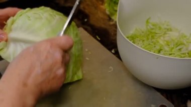 old women's hands with a knife cut cabbage on the cutting Board.