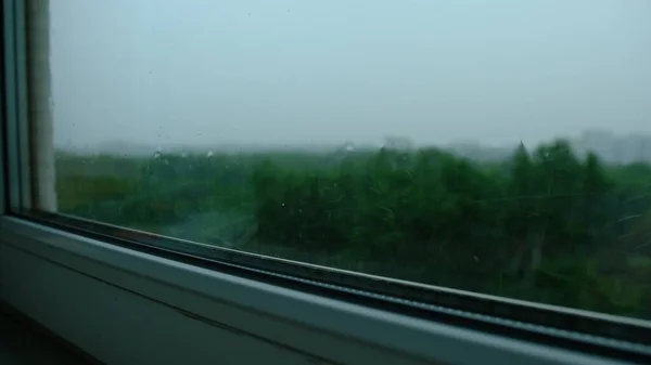 Raindrops on the window pane. Blurred background outside the window in the rain