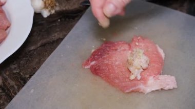 A delicious dish of pork mince wrapped with delicious pieces of bacon. Preparation of chevapchichi. Woman hands cooking meat rolls.