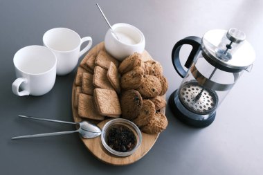 A tasty snack two cups of black tea and a plate of oatmeal cookies a wooden board on the gray background, leaf tea