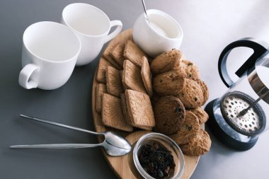 A tasty snack two cups of black tea and a plate of oatmeal cookies a wooden board on the gray background, leaf tea