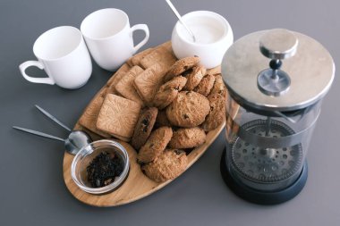 A tasty snack two cups of black tea and a plate of oatmeal cookies a wooden board on the gray background, leaf tea