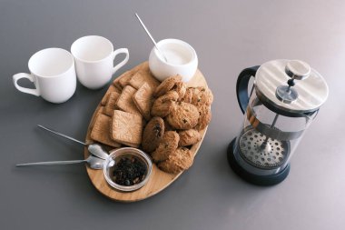 A tasty snack two cups of black tea and a plate of oatmeal cookies a wooden board on the gray background, leaf tea
