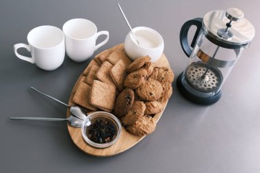 A tasty snack two cups of black tea and a plate of oatmeal cookies a wooden board on the gray background, leaf tea
