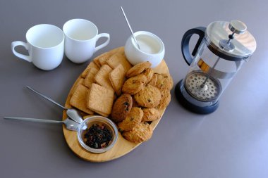 A tasty snack two cups of black tea and a plate of oatmeal cookies a wooden board on the gray background, leaf tea