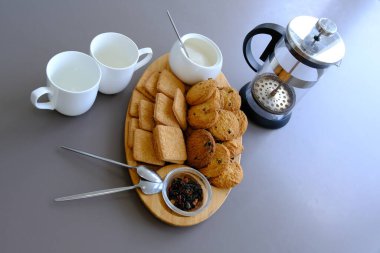 A tasty snack two cups of black tea and a plate of oatmeal cookies a wooden board on the gray background, leaf tea